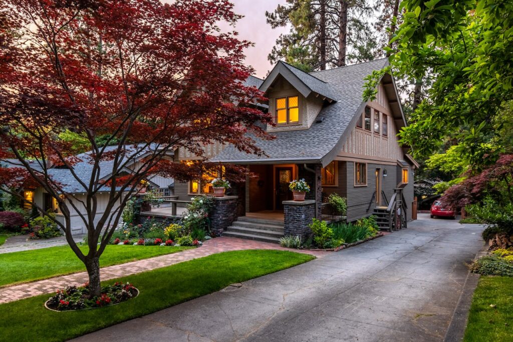 Beautiful suburban house with a red maple tree at twilight, showcasing elegant landscaping.